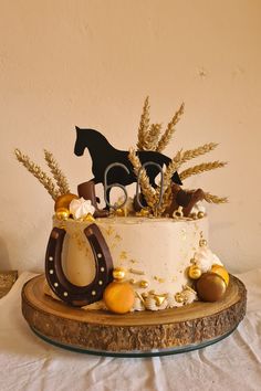 there is a cake decorated with horses and gold decorations on the top tier, sitting on a wooden platter