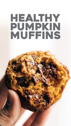 a hand holding a healthy pumpkin muffin in front of the camera with text overlay that reads healthy pumpkin muffins