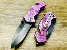 two pink and black knifes sitting on top of a wooden table next to each other