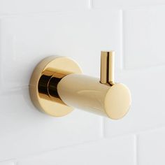 a gold robe hook on a white tile wall