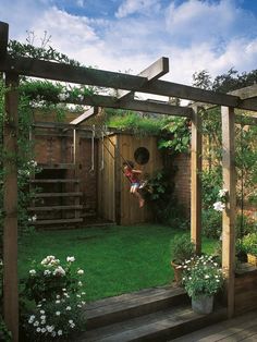 a person is hanging upside down in the yard with flowers and plants around them,