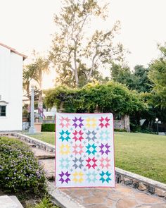 a colorful quilt sitting on top of a stone walkway