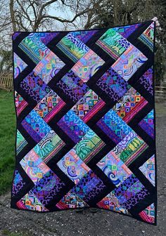 a colorful quilt hanging from the side of a tree