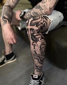 a man sitting on top of a couch with tattoos on his arm and leg sleeves