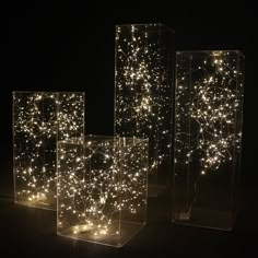 three clear boxes with lights in them sitting on a black surface and one is lit up