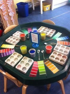 the table is covered with different colored trays and paintbrushes on it,