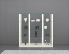 a white shelf with glass shelves filled with dishes and cups on it's sides