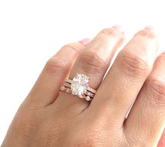 a woman's hand with a diamond ring on top of her finger and an engagement band