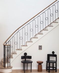 two chairs and a table sitting in front of a stair case next to a banister