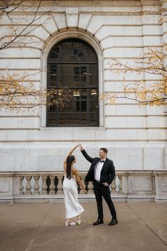 a man and woman dancing in front of a building