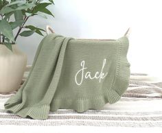 a green blanket with the word dad written on it next to a potted plant