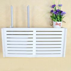 a white air conditioner sitting on top of a wall next to a potted plant