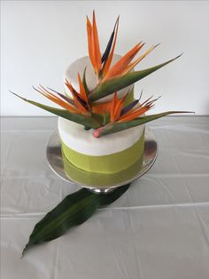 a cake with bird of paradise flowers on top is sitting on a white tablecloth