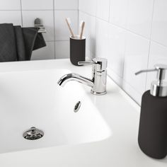 a bathroom sink with soap dispenser and toothbrush holder