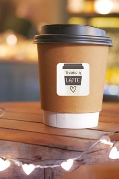 a coffee cup sitting on top of a wooden table with string lights strung around it