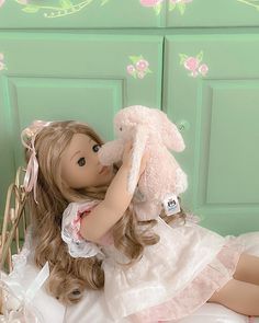 a doll laying on top of a bed next to a teddy bear