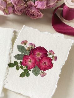 two pieces of paper with flowers on them next to some spools of thread