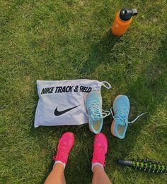 a pair of pink and blue shoes sitting on top of grass next to a bag