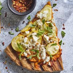 a slice of pizza with cheese and vegetables on it next to a bowl of sauce