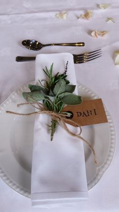 a place setting with napkins, silverware and greenery