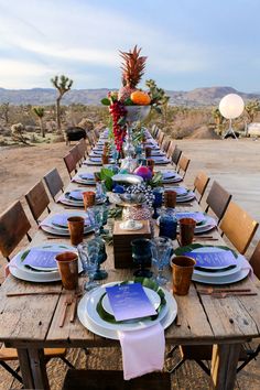 a long table set with plates and place settings for an outdoor dinner in the desert