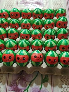 there are many green and red decorated eggs in a carton with faces on them