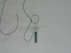 a pair of scissors with green string attached to them on a white sheeted surface