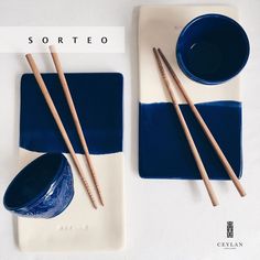 two plates with chopsticks on them next to a blue bowl and saucer