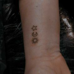 a small star and moon tattoo on the wrist