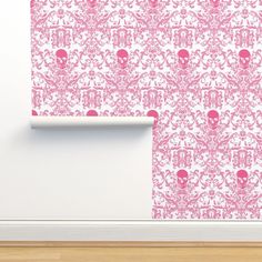 a pink wallpaper with skulls on it and a white frame in the middle, next to a wooden floor