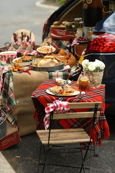 a table with food and drinks on it next to a car parked in the street