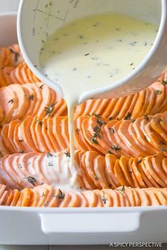 the dressing is being poured on sweet potato wedges in a white casserole dish