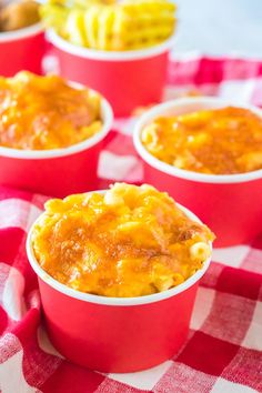 three red cups filled with macaroni and cheese on a checkered tablecloth