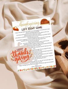 a thanksgiving letter to the left right game is on top of a white sheet with an orange and black cat laying next to it