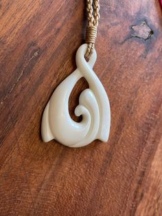 a white ceramic object is hanging on a wooden table with red cords and a brown cord