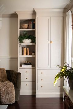 a living room filled with furniture and bookshelves next to a window on top of a hard wood floor