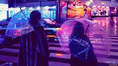 two people walking down the street with umbrellas in their hands, at night time