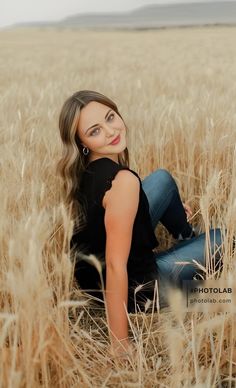 a woman sitting in the middle of a wheat field