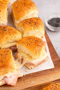 ham and cheese sliders cut in half on a cutting board with black pepper sprinkles