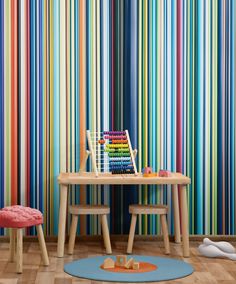 a child's desk and chair in front of a multicolored striped wall