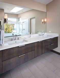 a bathroom with double sinks and large mirrors