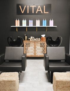 a salon with two black chairs and a table in front of the wall that says vital