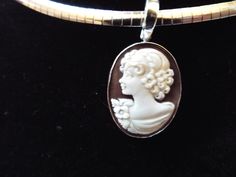 "This is a hand carved sardonyx cameo measuring 20 mm (0.79\") by 25 mm (0.98\") set in sterling silver. Bail is an enhancer of 5 mm in size, so it will accommodate a chain up to 4 mm (0.15\"). This cameo is a carved portrait of a women by Sorriso. It is absolutely beautifully carved and it comes packed in a black velvet box and certificate of authenticity for gift giving. Chain included. Welcome to CASCO Cameos, LLC. CASCO Cameos is the sole provider of cameos in North America. The founding com Silver Cameo Round Jewelry, Silver Cameo Round Pendant Jewelry, Silver Cameo Jewelry With Round Pendant, Collectible Cameo Jewelry With Round Pendant, Collectible Cameo Round Pendant Jewelry, Silver Cameo Oval Pendant Jewelry, Silver Oval Cameo Pendant Jewelry, Oval Cameo Sterling Silver Jewelry, Formal Oval Sterling Silver Cameo Jewelry