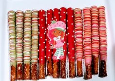 there are many cookies and candy sticks in the box on the table, one is decorated with a girl