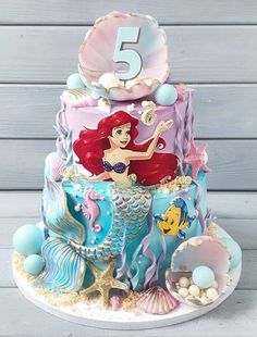 the little mermaid cake is decorated with blue and pink icing, under an ocean theme