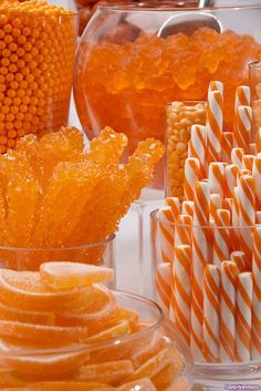 candy and candies are arranged in glass containers on a table with orange striped straws