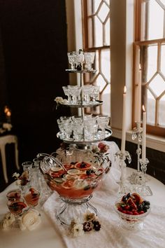 a table topped with lots of desserts on top of a white cloth covered table