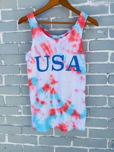 an american flag tie dye tank top hanging on a brick wall with the word usa printed on it