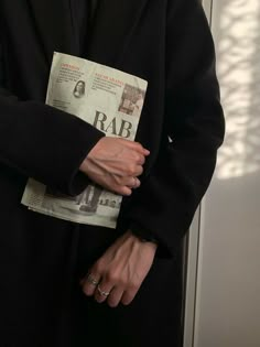 a person in a black coat is holding onto a newspaper