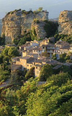 an old village nestled on top of a rocky cliff in the distance, surrounded by lush green trees